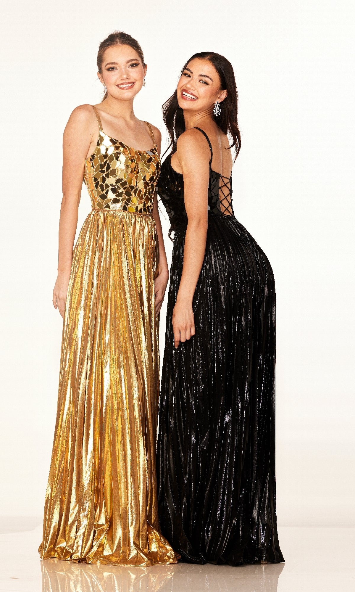 Two women stand side by side in formal gowns; one wears a gold dress with an embellished bodice, the other wears the black Cecilia Couture 2609, a long pleated A-line prom dress with a lace-up back.